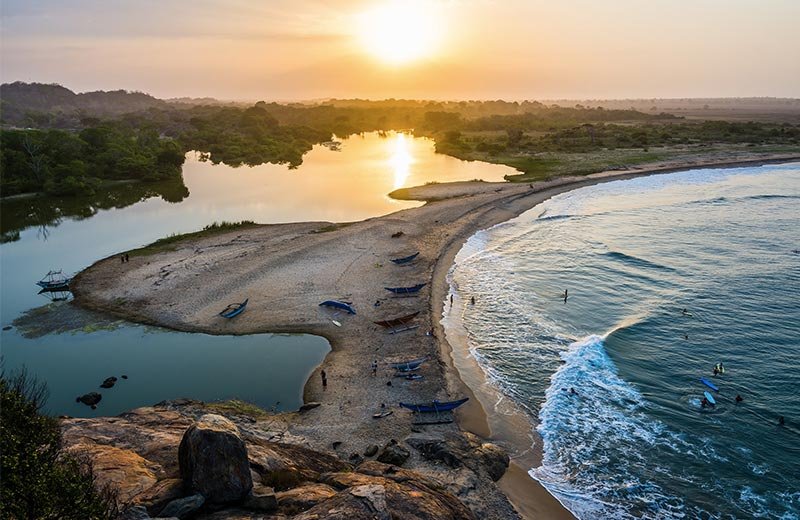 arugam bay beach at sunset view with people surfing